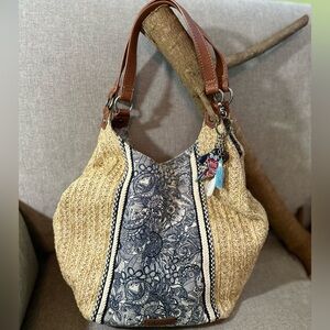 Straw/canvas with leather straps & leather/snapping closure.  Owl/tassels accent